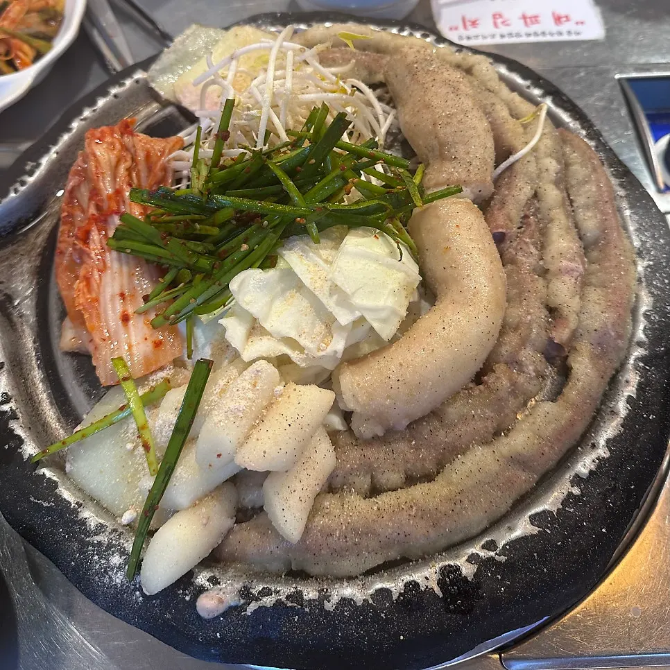 둥근 불판에 올라간 곱창과 부추, 떡, 김치
