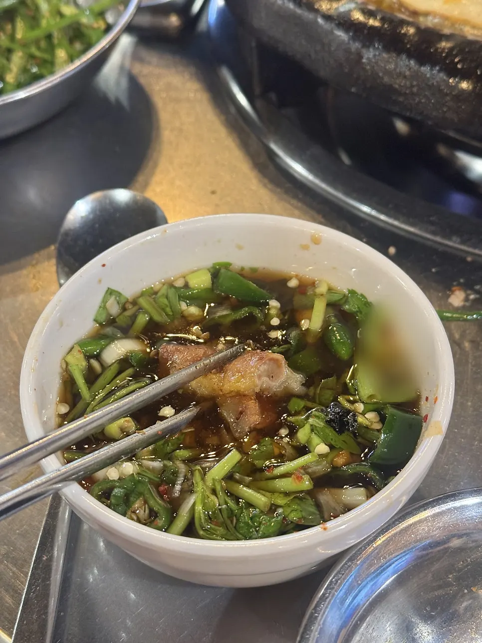 A piece of gopchang dipped in mijeolma sauce