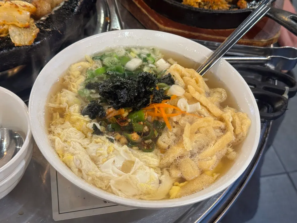 Anchovy noodles topped with egg, seaweed flakes and fried tofu skin