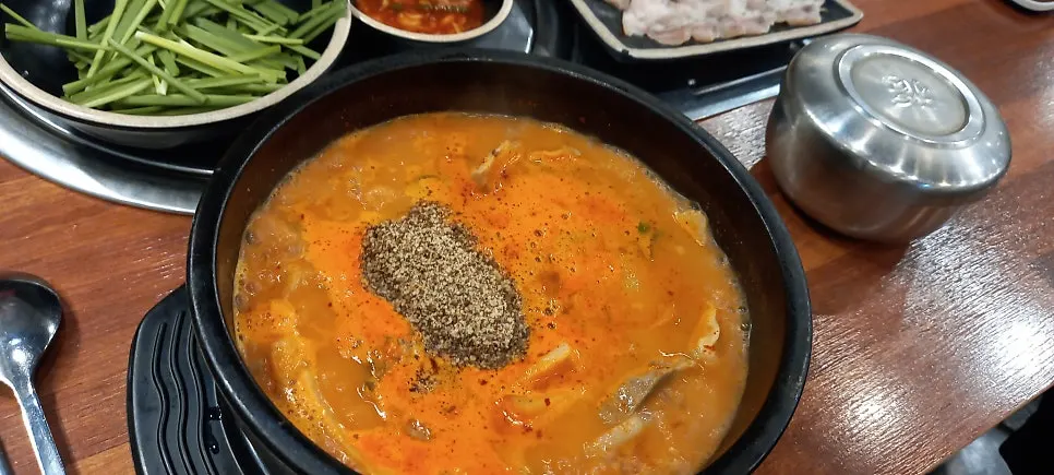 A plate of chives and kimchi side dishes next to the gukbap