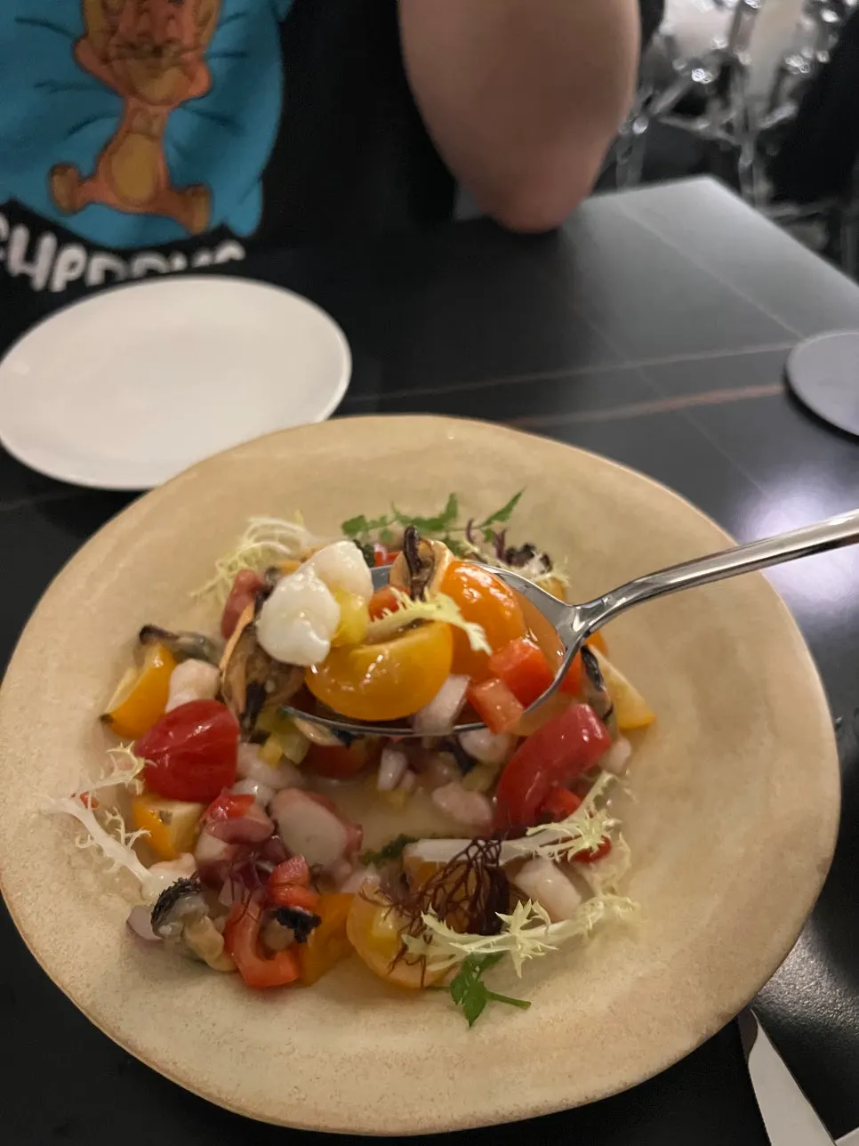 A spoonful of salad with cherry tomatoes and seafood together