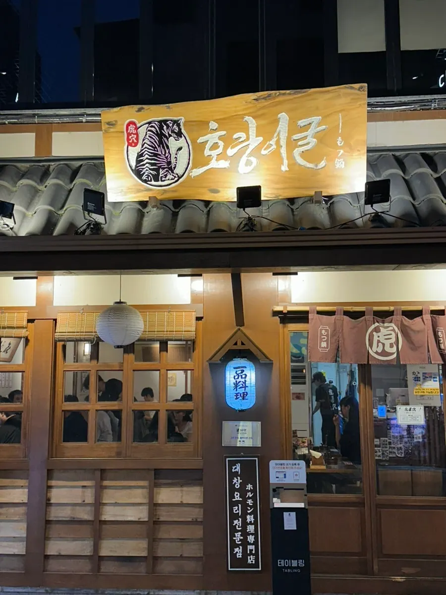 우드톤 외관과 간판이 보이는 호랑이굴 방이점 입구