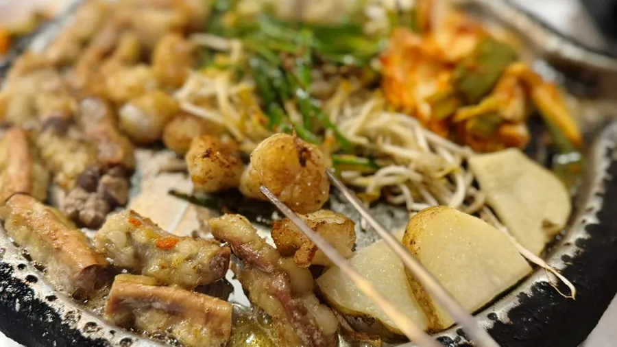 A piece of gopchang dipped in mijeolma sauce