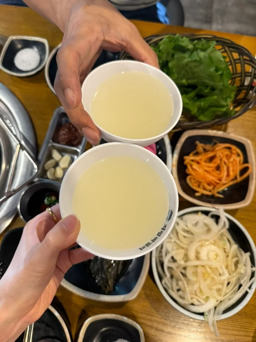 Jipyeong raw makgeolli poured into a glass next to grilled meat