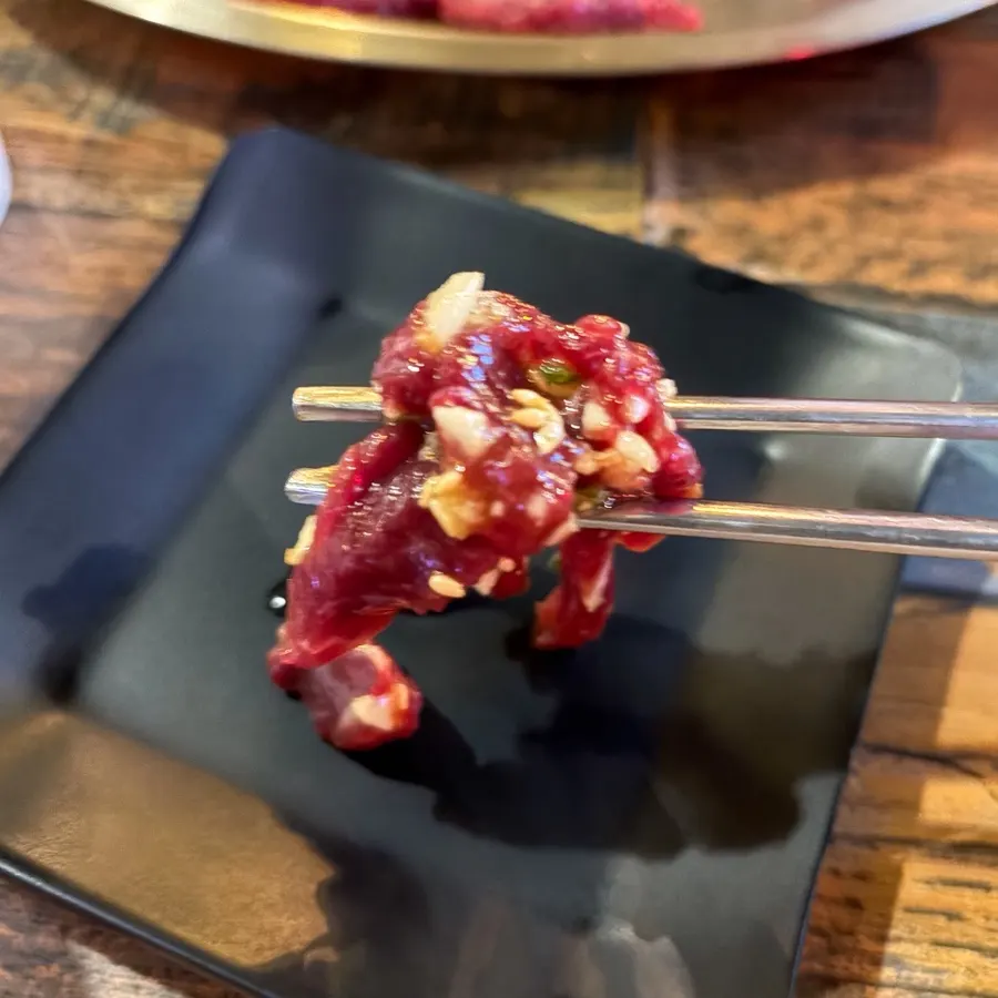 A piece of yukhoe picked up with chopsticks