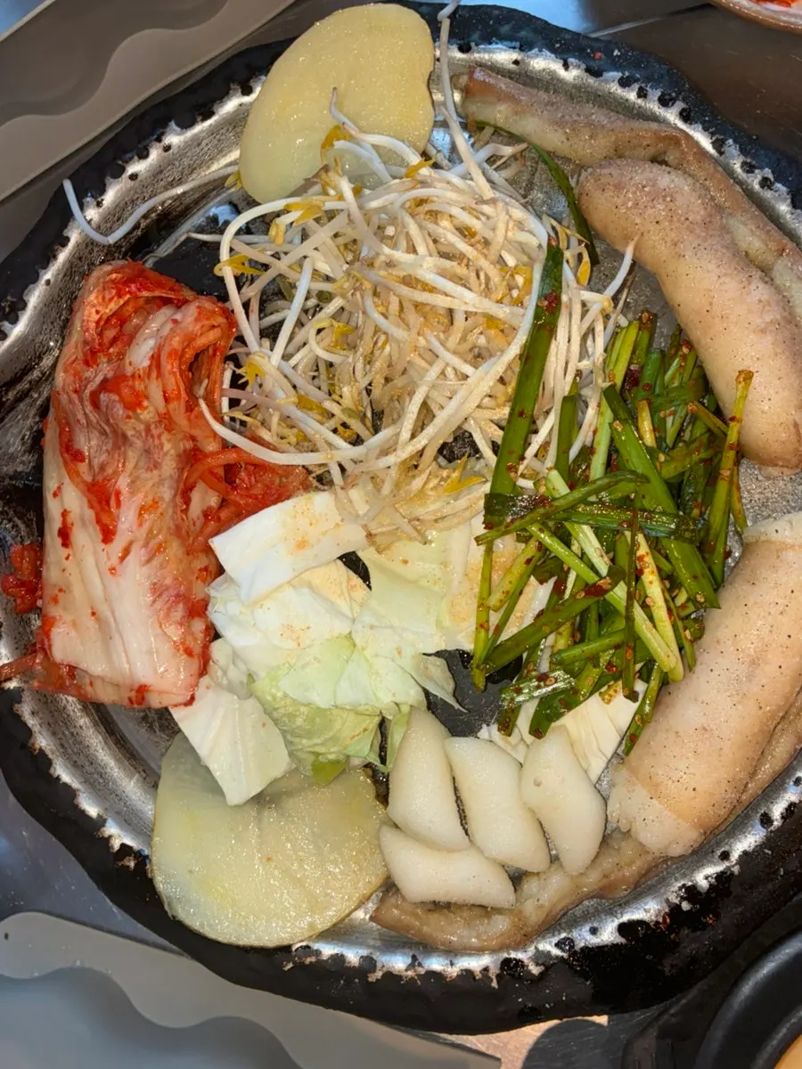 Gopchang and accompanying ingredients on the grill