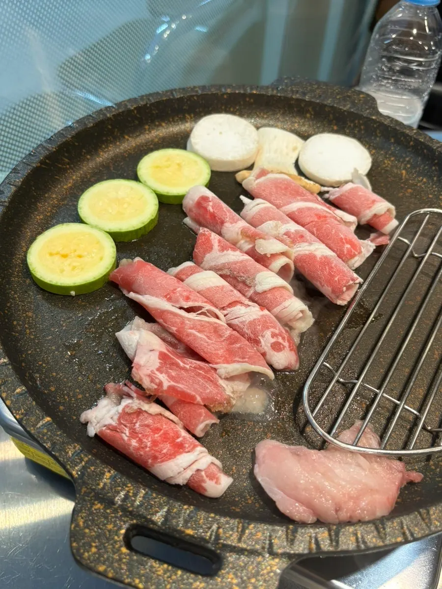 Thin slices of usamgyeop and vegetables on the grill