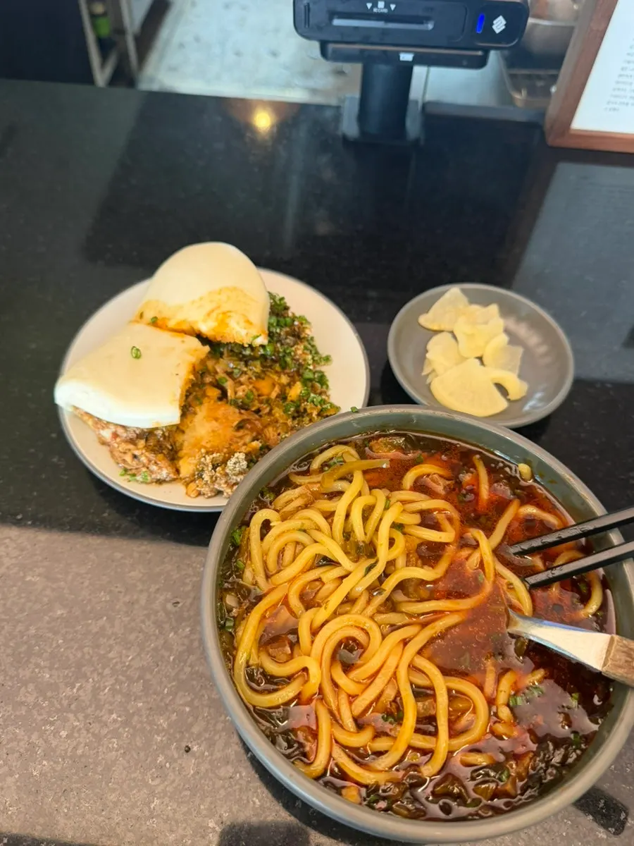 Beef noodle soup and bao laid out on the table