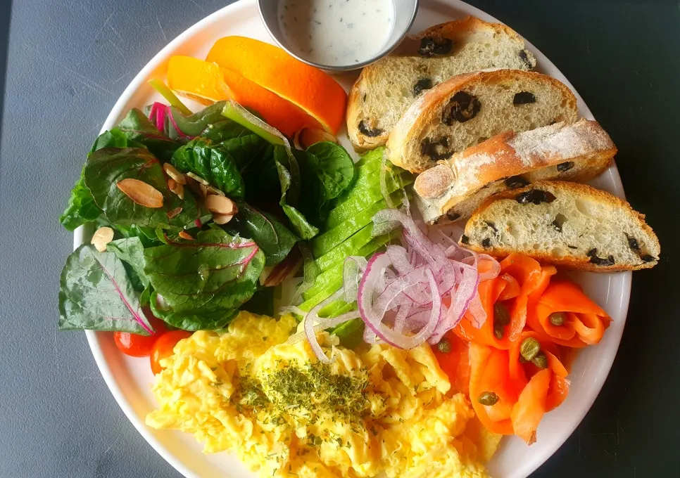 A plate of brunch topped with salmon and avocado