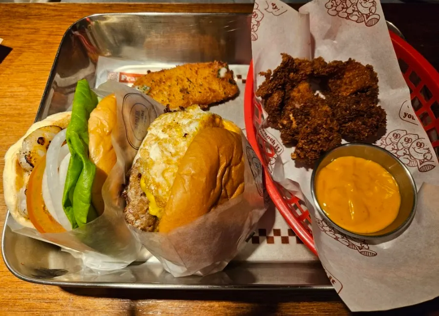 Two burgers and sides laid out on the table