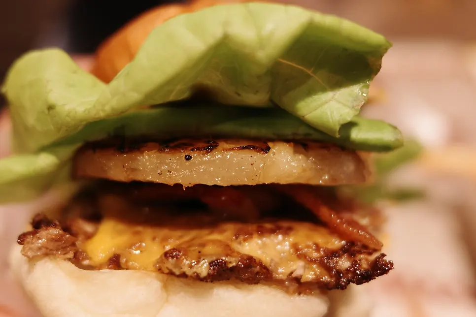 Inside the burger showing beef patties, hash brown, and vegetables
