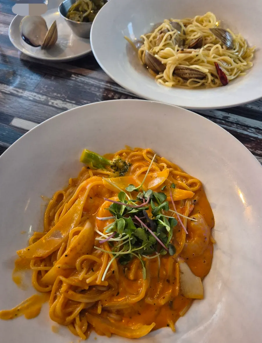 Mesa con pasta acompañada de pepinillos y platos