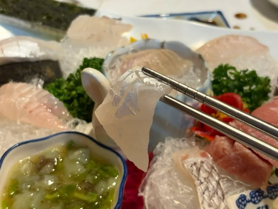 A piece of sashimi with soy sauce and wasabi