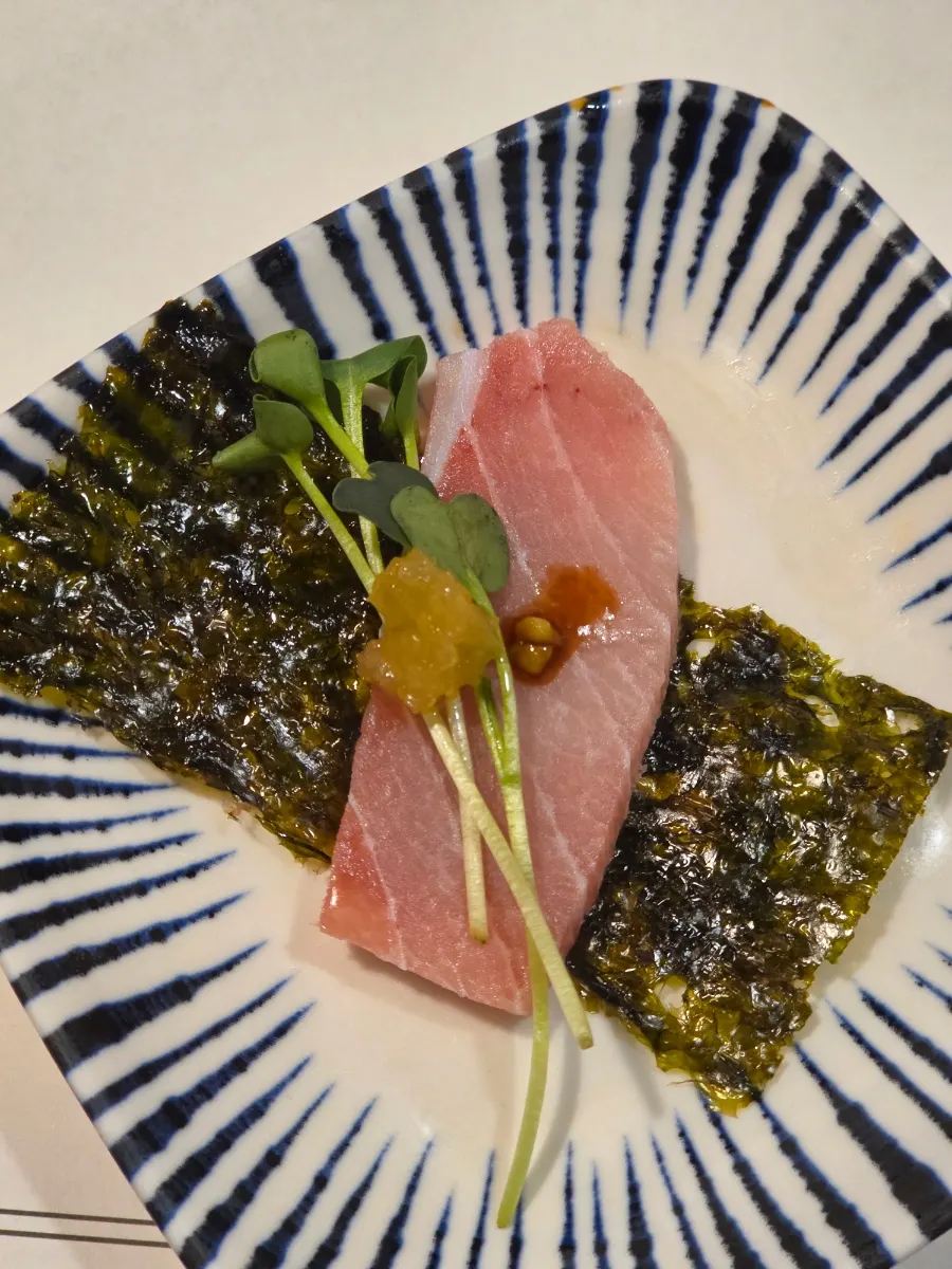 Tuna sashimi served with seaweed, radish sprouts, and sesame oil sauce