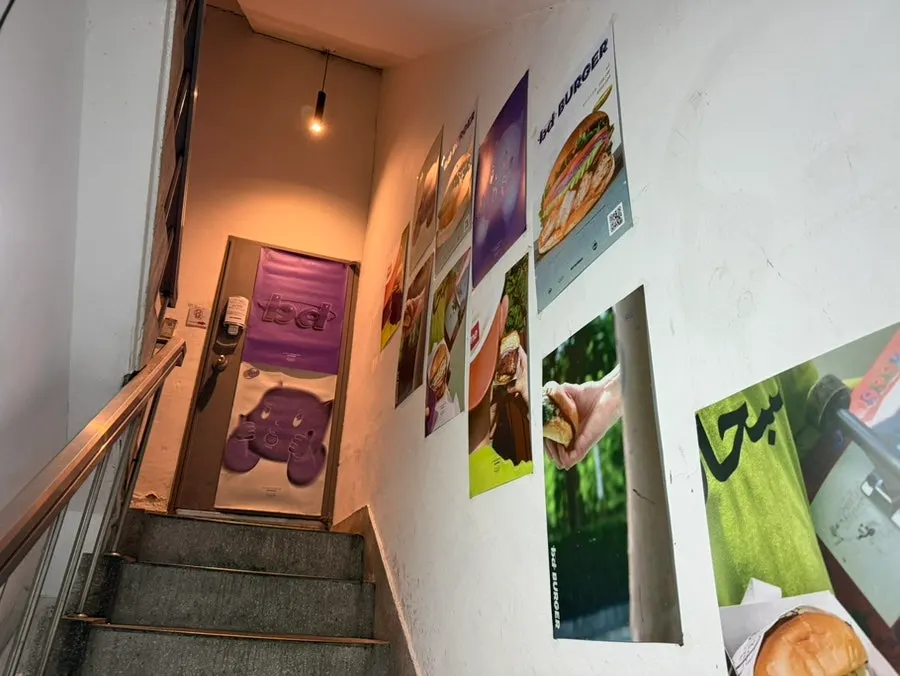 Poster-covered staircase leading up to bd Burger Seongsu's 2nd floor