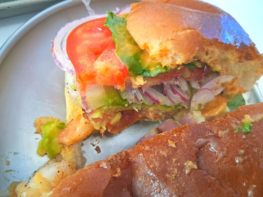 A bite of the shrimp avocado burger showing the whole shrimp