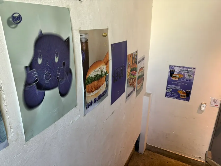 Burger shop posters covering the stairwell wall
