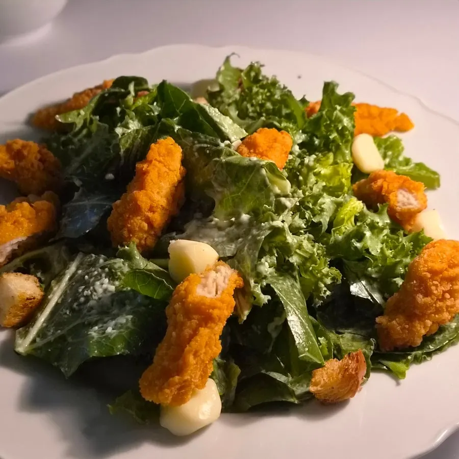 A plate of Caesar salad with chicken tenders