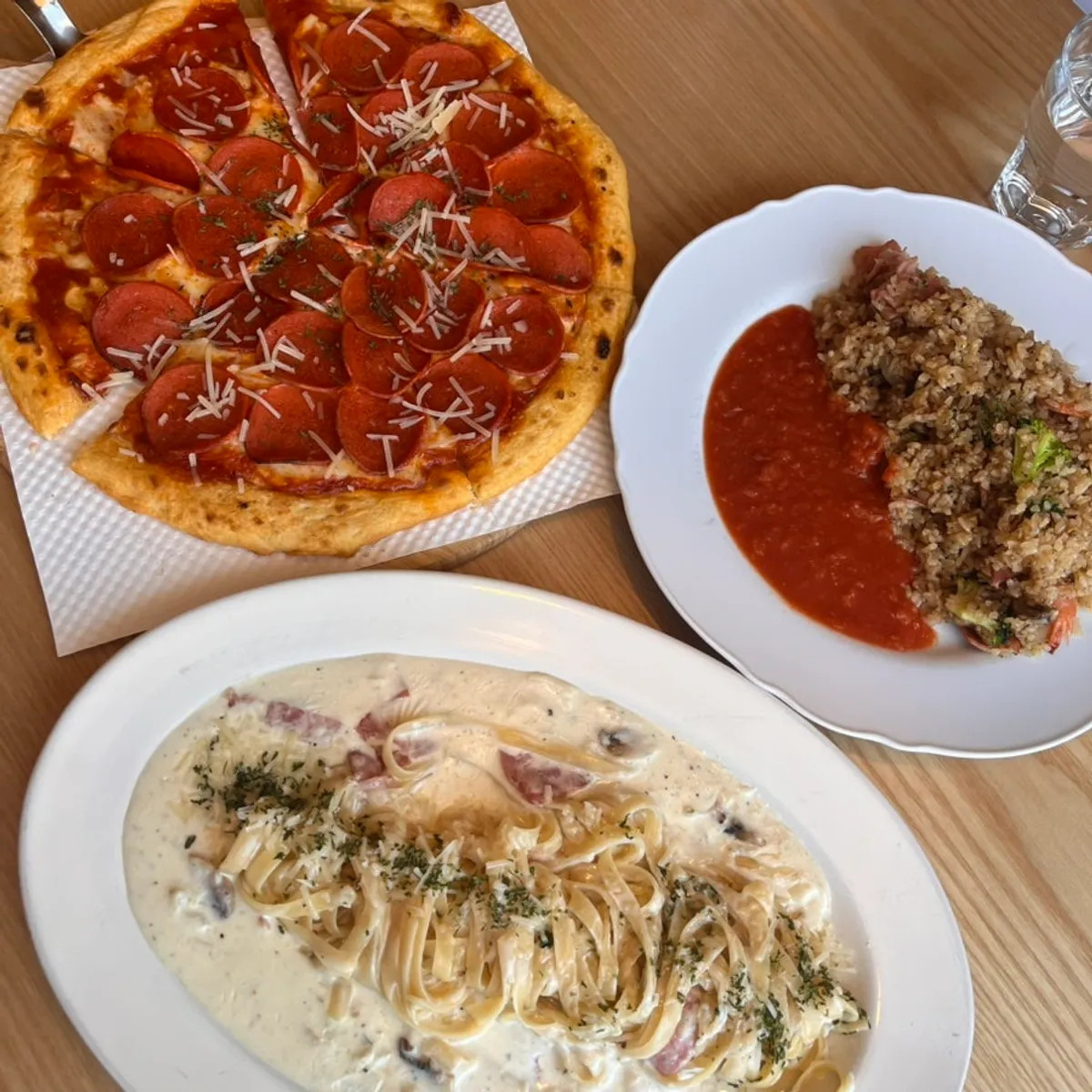 Pasta, pizza and pilaf laid out on the window-side table