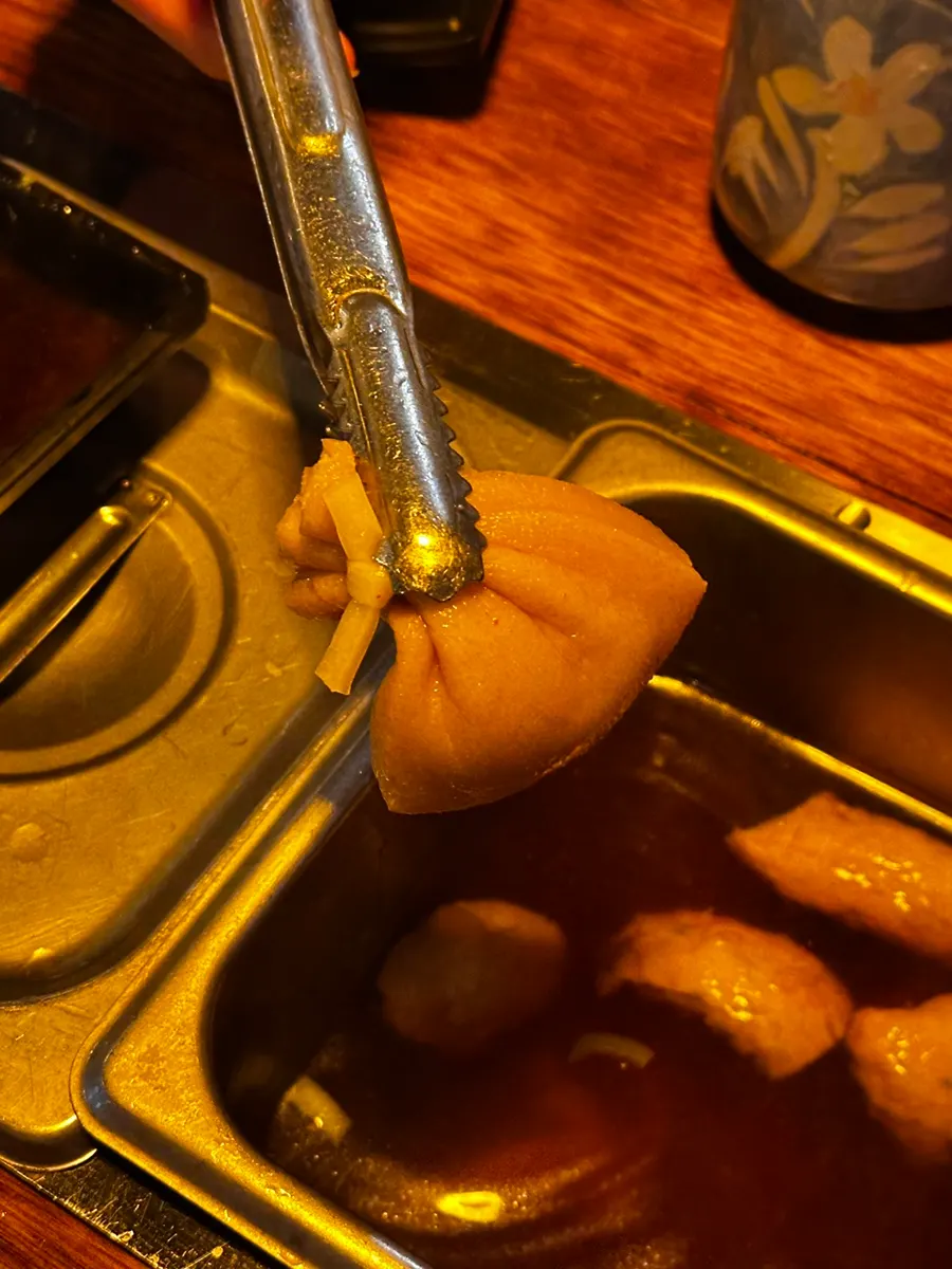 Fish cake skewers dunked in the table warmer broth