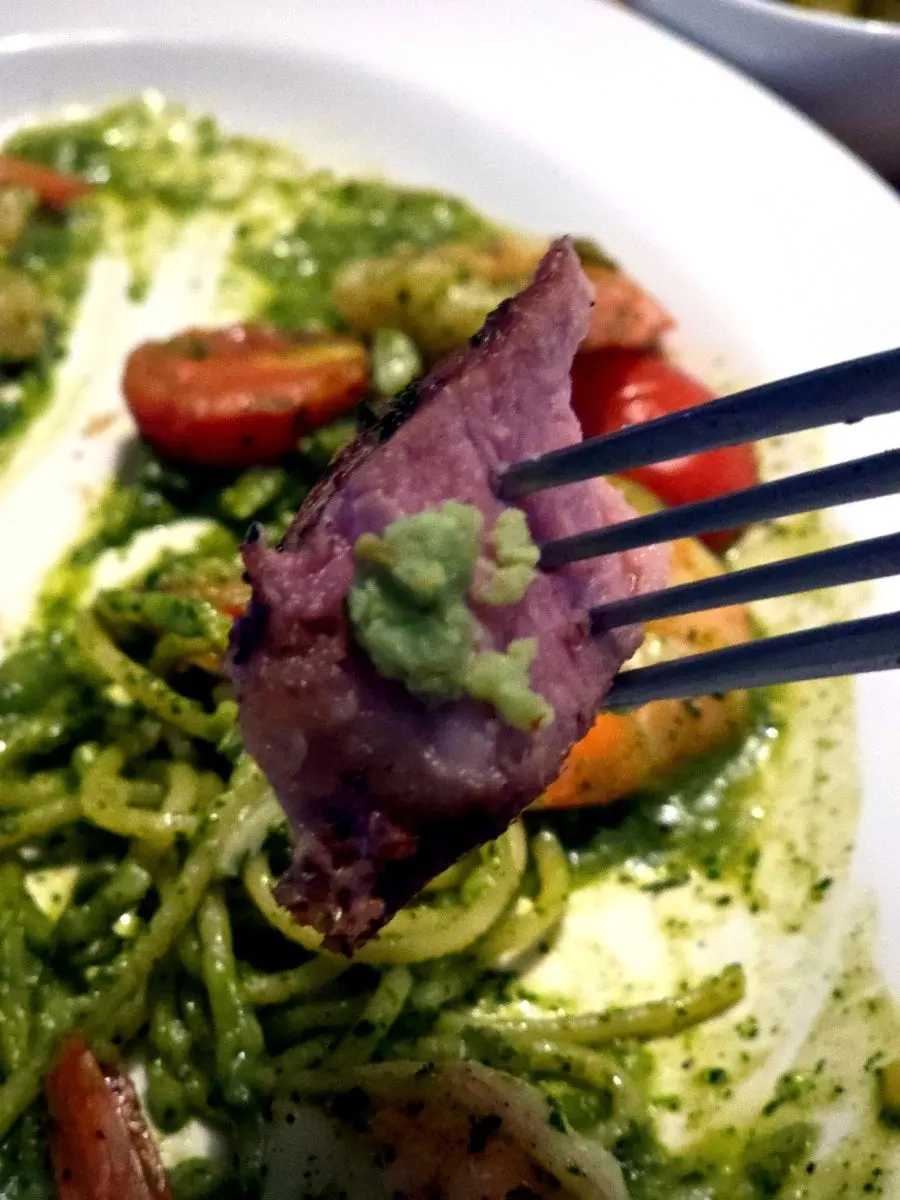 A piece of sous-vide pork neck dipped in sauce