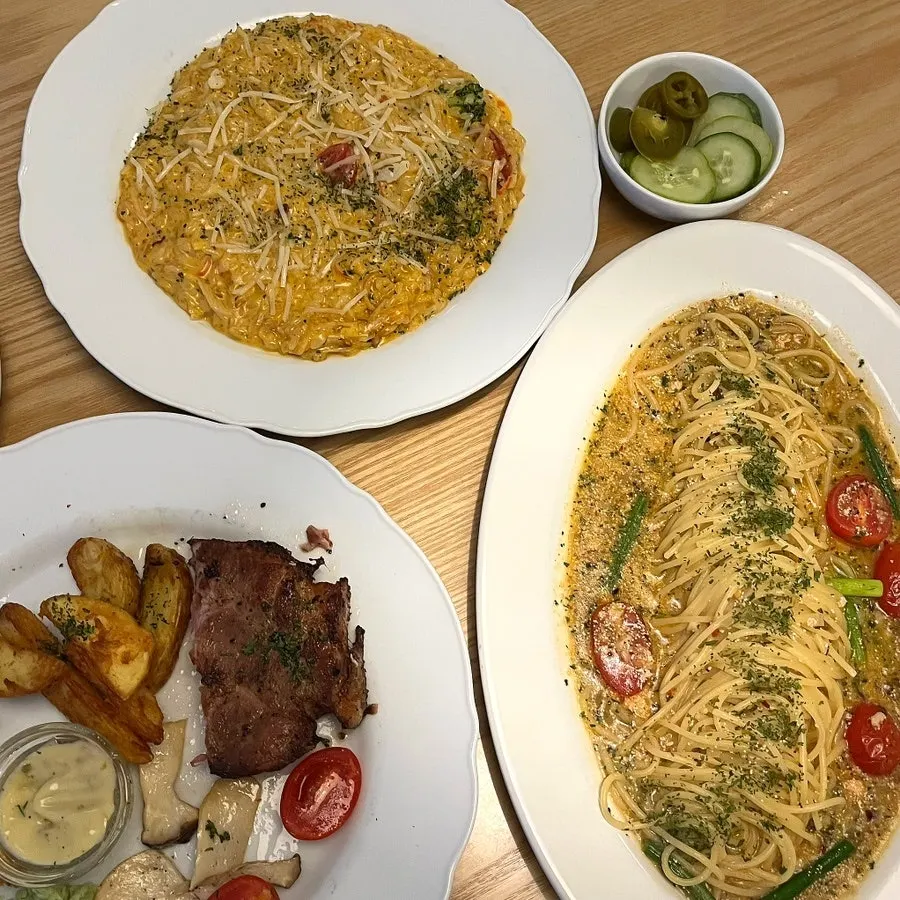 Table set with risotto, pasta, and sous-vide pork neck
