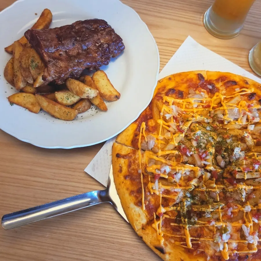 Table with chicken potato pizza, pork rib half order, and two draft beers