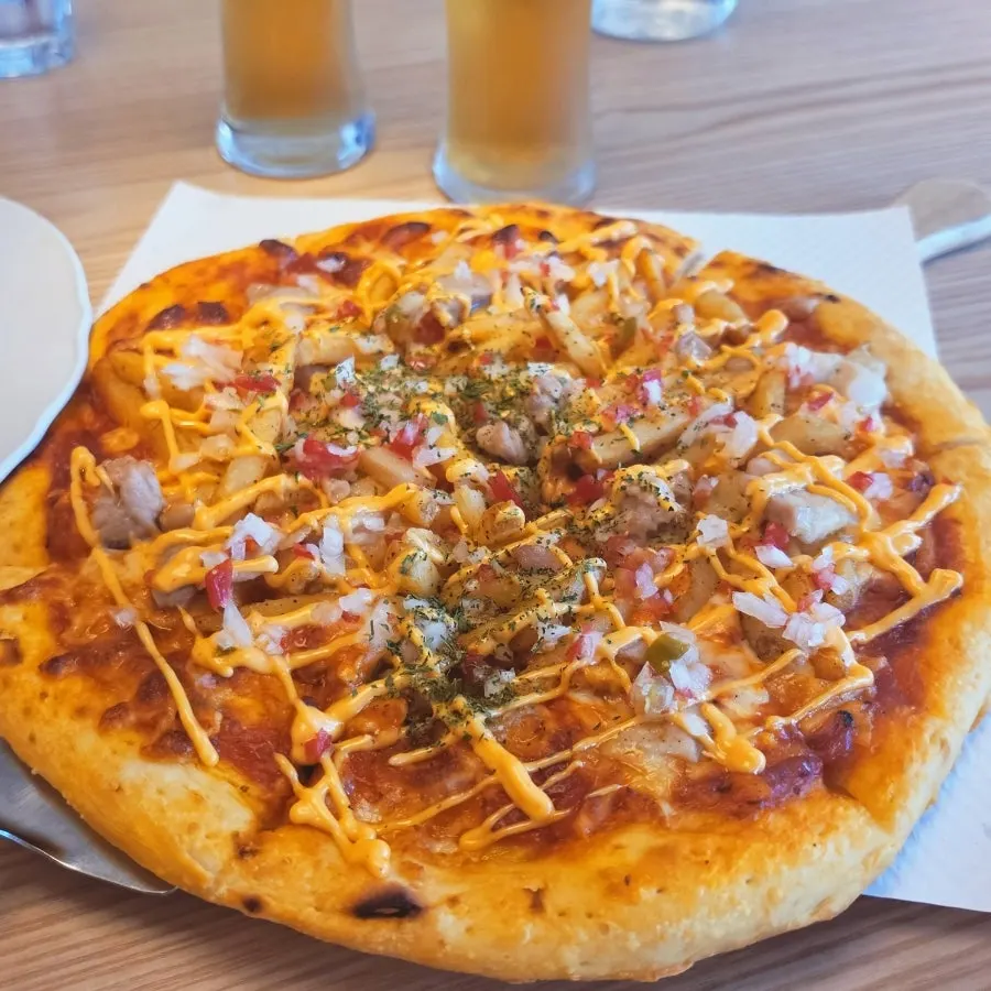 Close-up of chicken potato pizza piled high with toppings