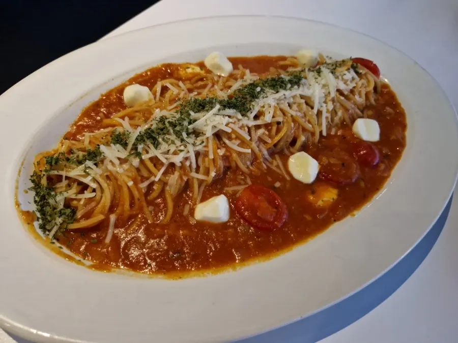 Orange juice served alongside pasta on the table