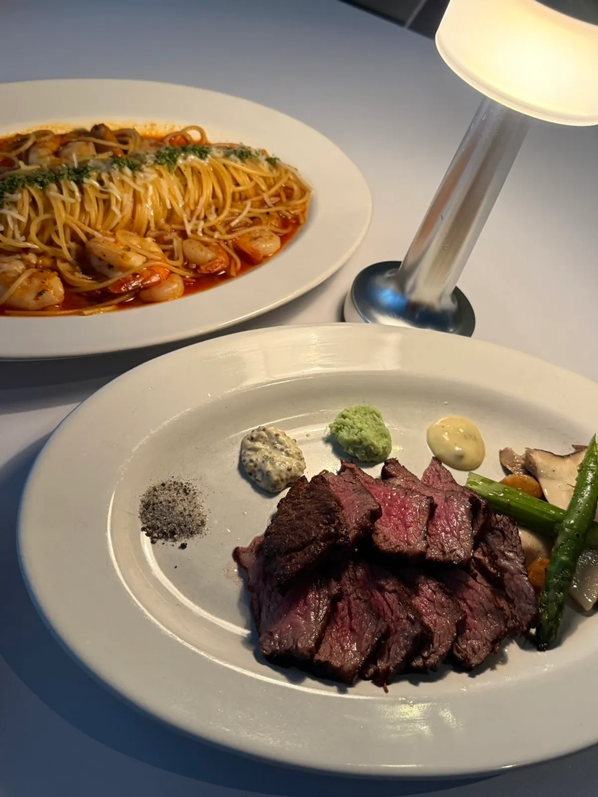 Chuck flap steak and hot shrimp garlic pasta set on the table