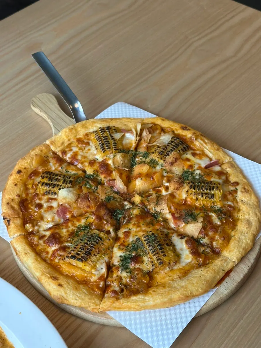 A slice of corn pizza with thin crust