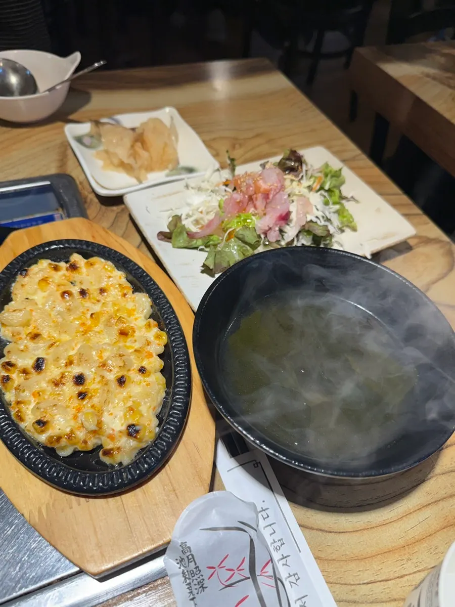 Side dish spread with corn cheese, seaweed soup, and seasoned raw fish