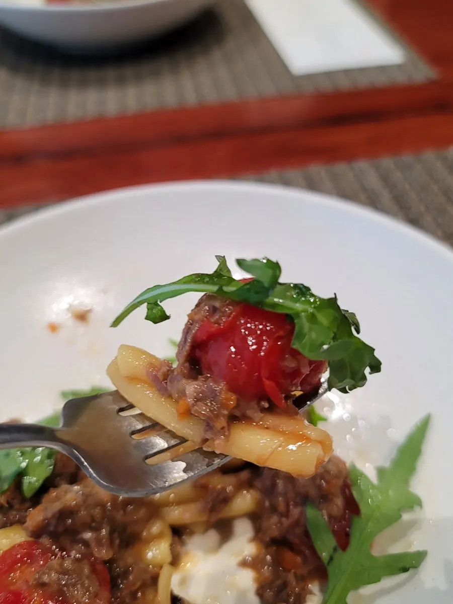 Close-up of ragu pasta topped with seared tomato