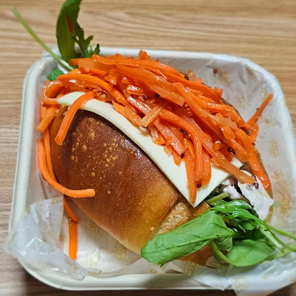 Carrot râpée chicken sandwich topped with shredded carrot