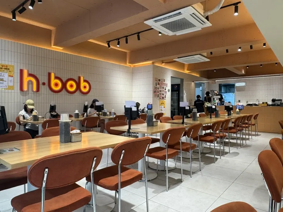 Interior with white tile walls and the h·bob neon sign