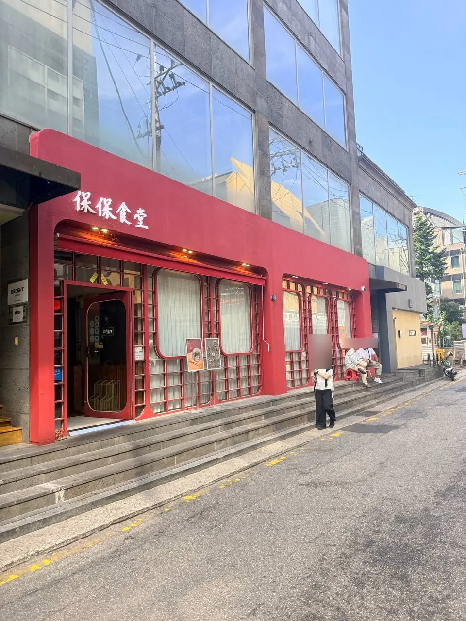Red-walled building on a sloped alley with the restaurant above a flight of stairs