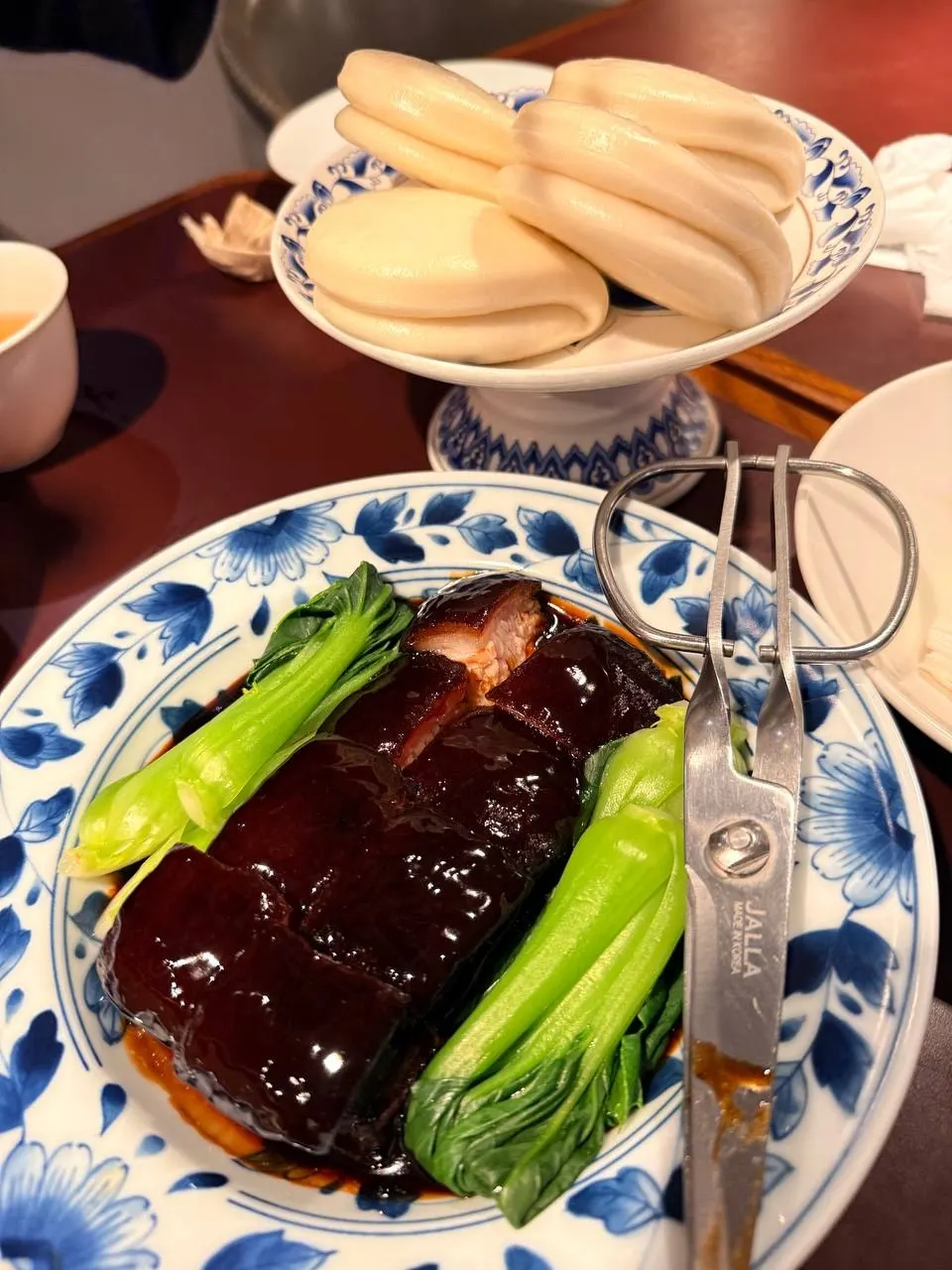 Dongpo pork on a blue-and-white porcelain plate with steamed buns on a footed dish