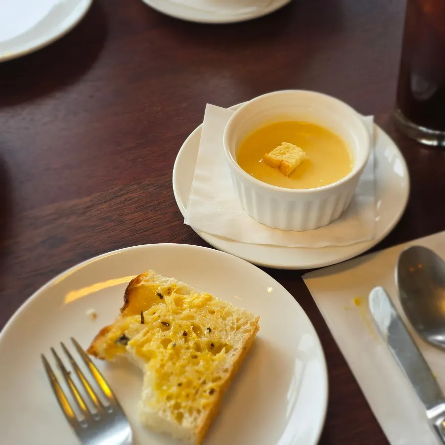 Table setting with bread, sweet corn soup, and half salad