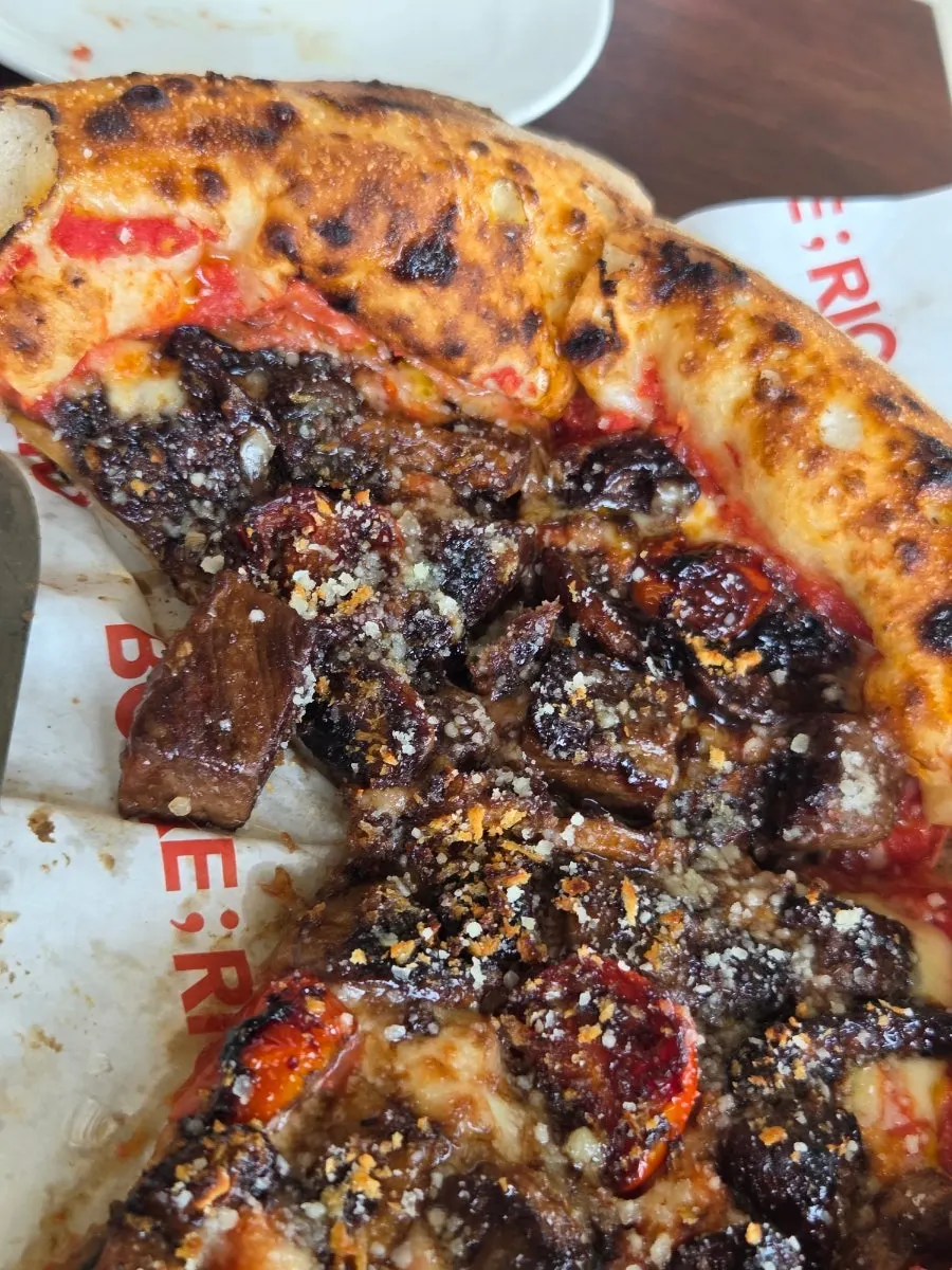 A slice of pizza topped with big chunks of Korean beef