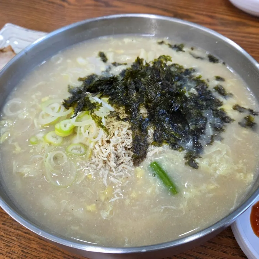 Dak kalguksu topped with egg, gim flakes, and scallion