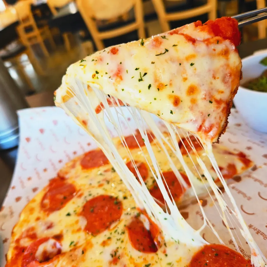 A slice of pepperoni pizza with stretching cheese