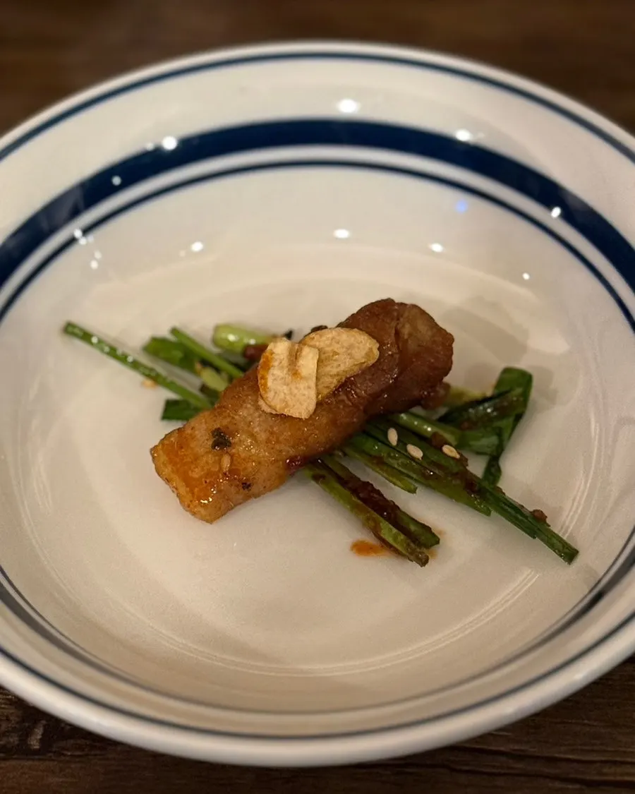 A piece of spicy pork belly wrapped in seasoned chives
