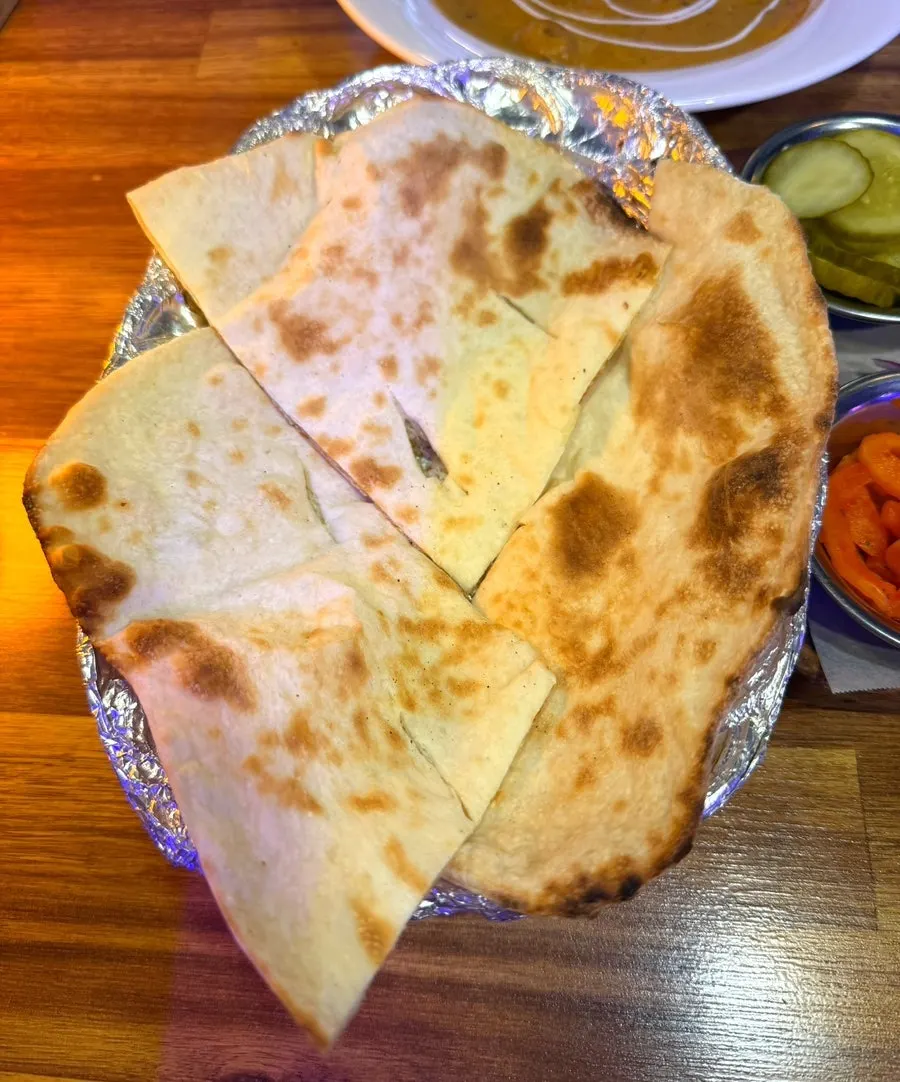 Tearing naan and dipping it into coconut shrimp curry