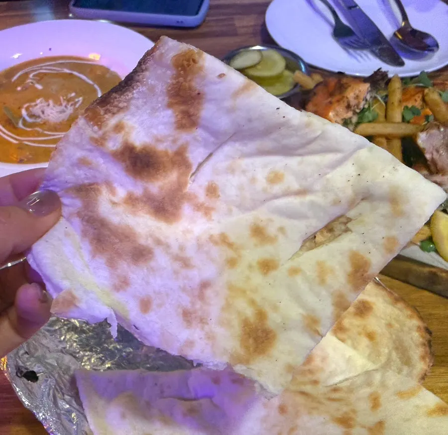 Naan with crispy edges alongside the curry