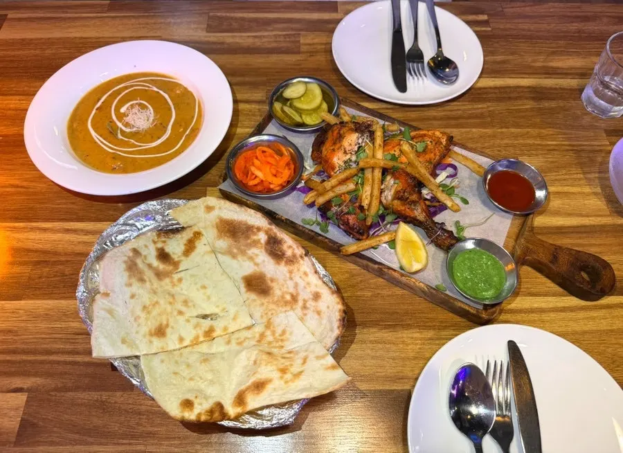 Table setting with tandoori chicken and coconut shrimp curry together