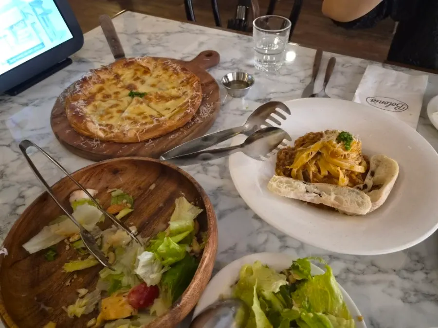 Table spread with salad, pizza, and pasta together