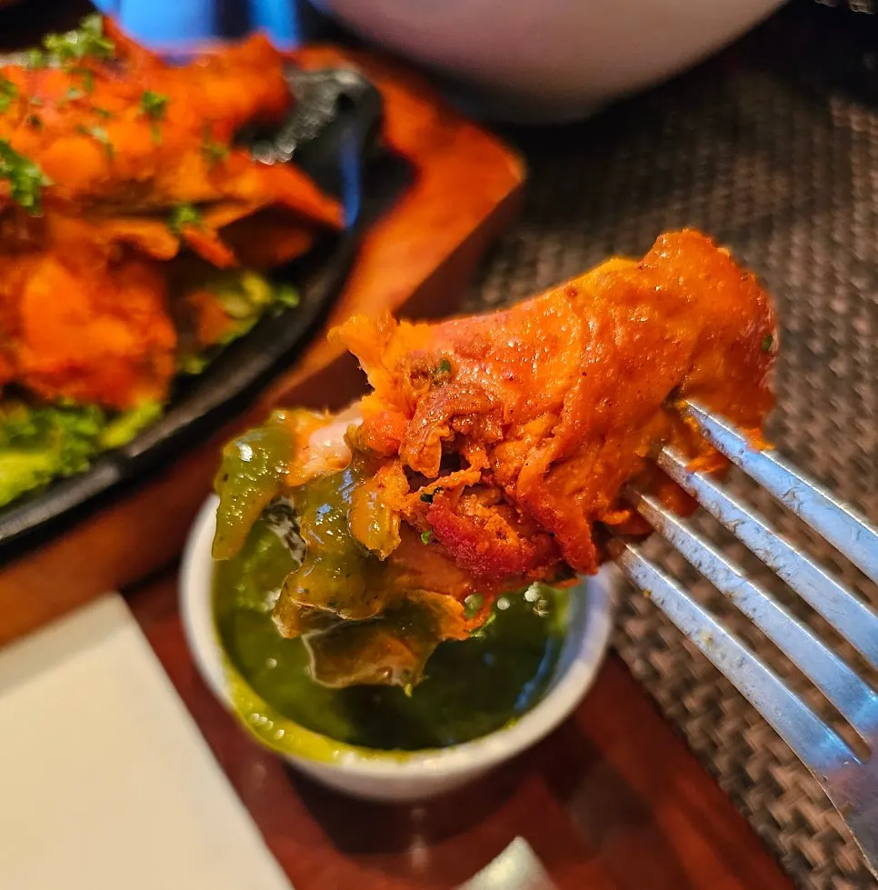 Dipping tandoori chicken into the sauce