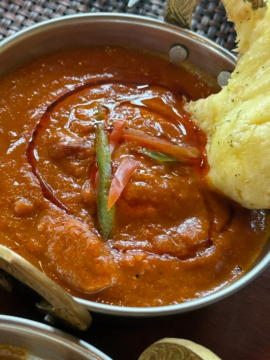 A bite of naan topped with tandoori chicken