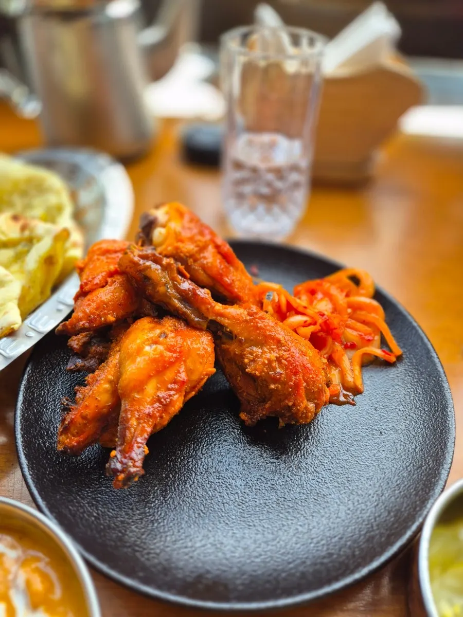 A plate of tandoori chicken served with an onion side dish