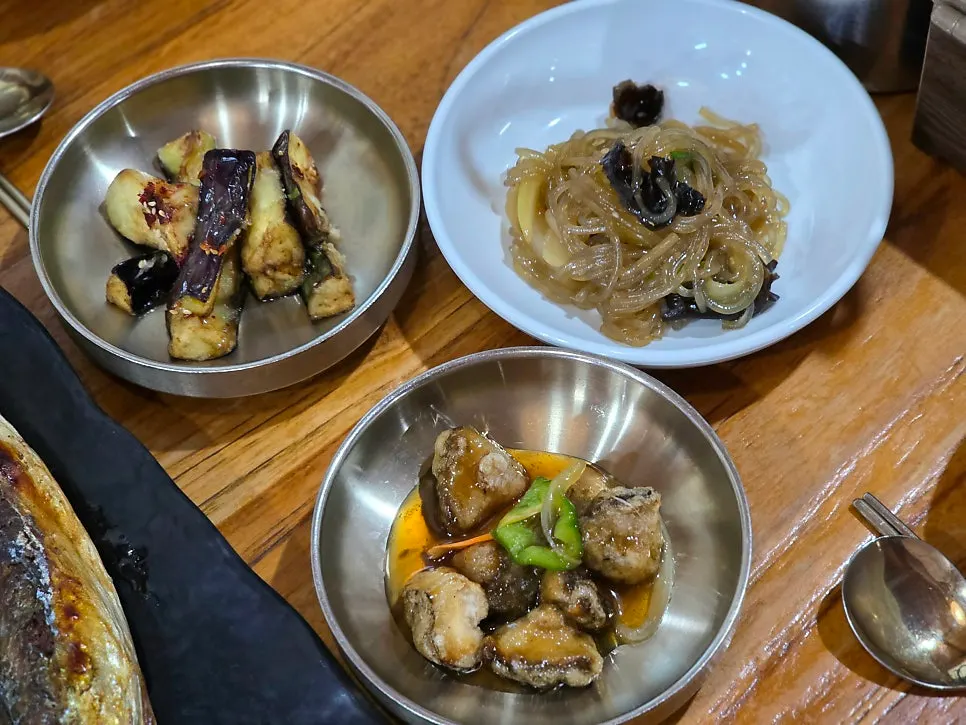 Plates of lotus root salad, japchae, and mushroom sweet-and-sour dish